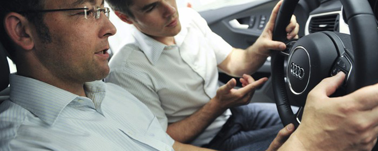 two men inspecting and discussing buttons on a steering wheel